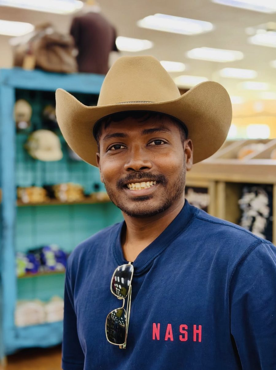 Ganesha smiling in a tan cowboy hat and navy NASH tee